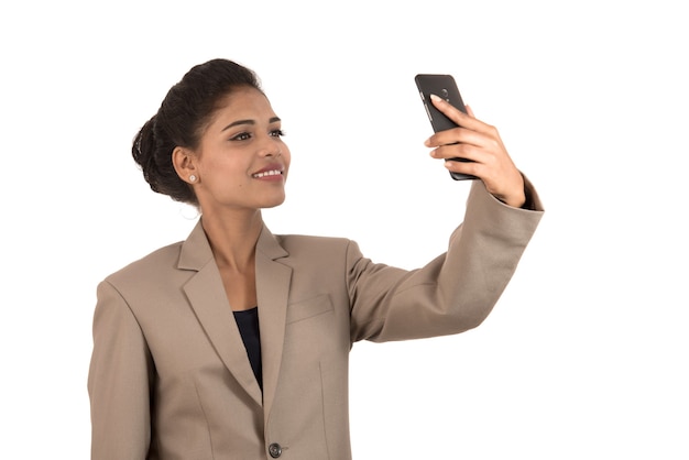 Hermosa joven empresaria con smartphone para tomar fotos selfie aislado sobre fondo blanco.