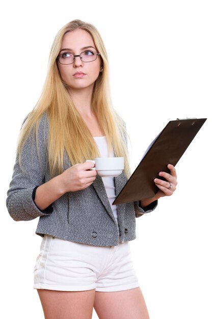 Hermosa joven empresaria sosteniendo portapapeles y taza de café