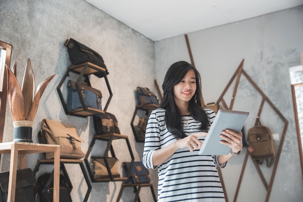 Hermosa joven empresario en una tienda de bolsos con tableta