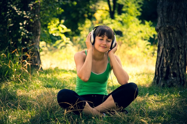 Hermosa joven escucha música en un parque