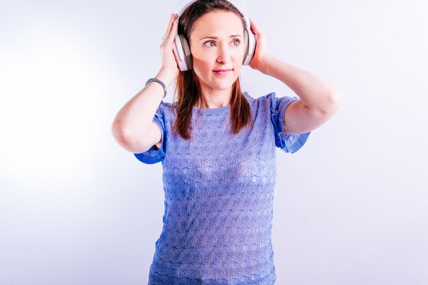 Hermosa joven escuchando música con auriculares sobre fondo blanco.