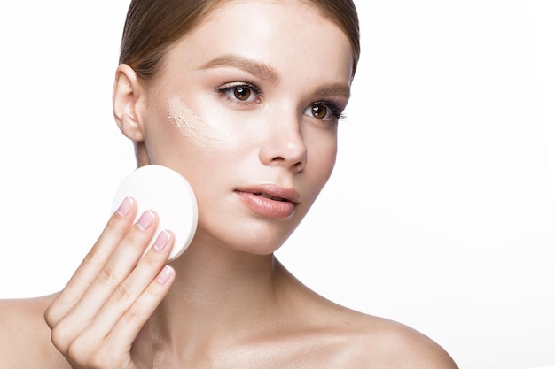 Hermosa joven con esponja para aplicar maquillaje y manicura francesa. rostro de belleza. Foto tomada en el estudio sobre un fondo blanco.