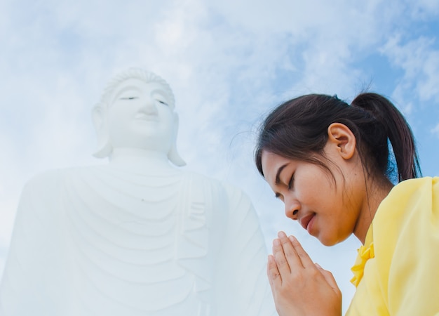 Hermosa joven está adorando al Buda.