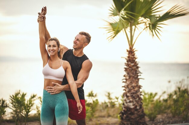 Una hermosa joven está haciendo ejercicio de estiramiento en la playa con el apoyo de su sofá