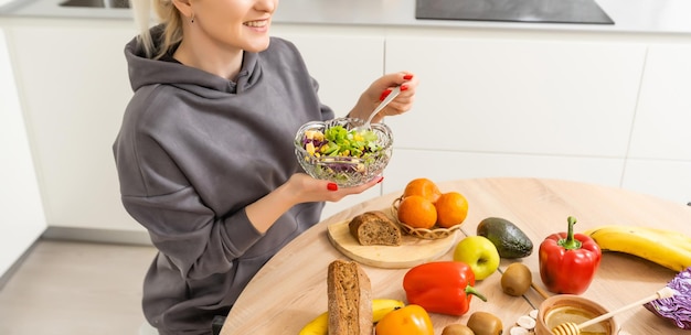 Hermosa joven está preparando ensalada de verduras en la cocina. Cocinar En Casa.