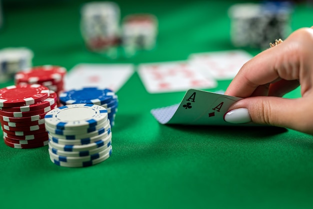 Hermosa joven está sentada en una mesa de póquer con cartas en las manos