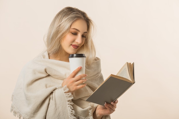 hermosa joven está tomando café y leyendo un libro