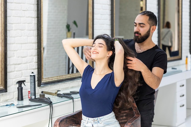 Hermosa joven estirando su largo cabello con su peluquero Foto de alta calidad