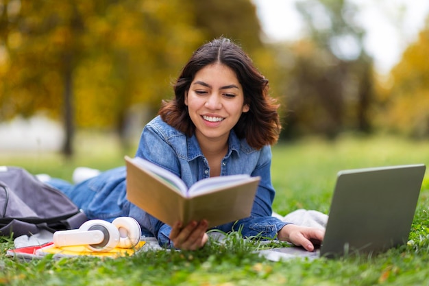 Hermosa joven estudiante árabe estudio con libro y portátil al aire libre