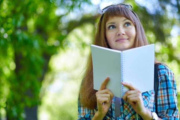 Hermosa joven estudiante leyendo un libro en el parque verde de verano