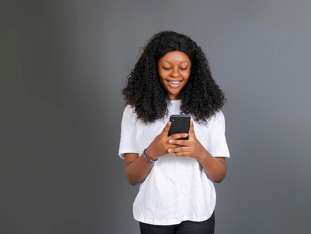 Hermosa joven estudiante negra usando y mirando el teléfono inteligente