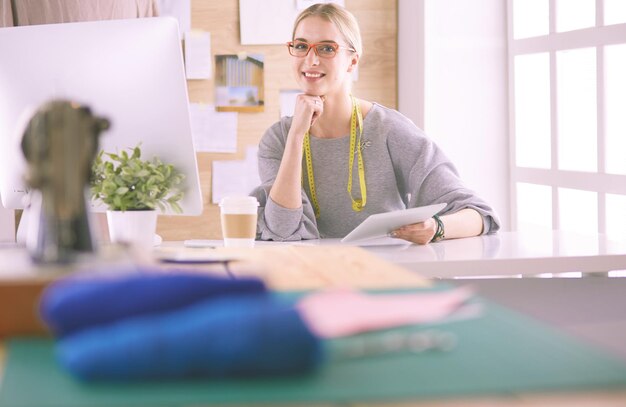 Hermosa joven en una fábrica con una máquina de coser en la mesa