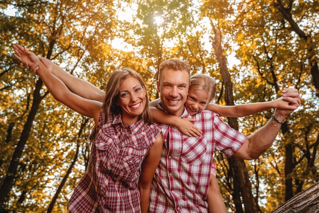 Hermosa joven familia disfrutando de un paseo por el bosque.