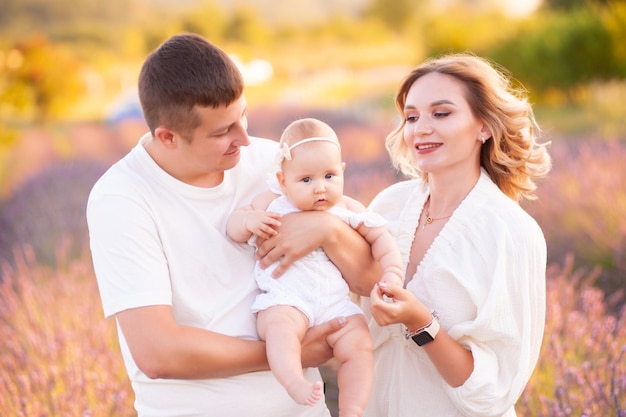 Hermosa joven familia, padre y madre con bebé en campo de lavanda