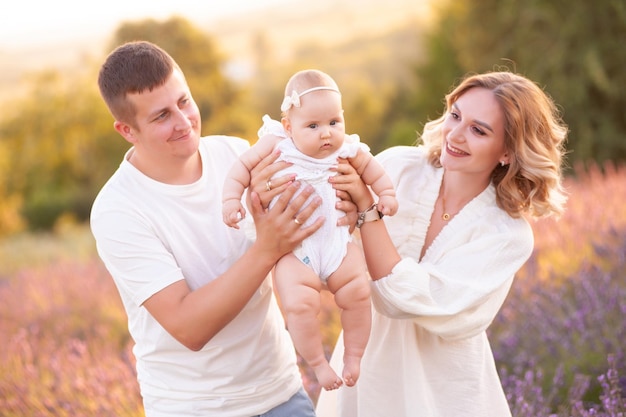 Hermosa joven familia, padre y madre con bebé en campo de lavanda