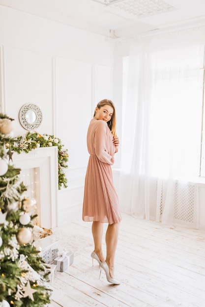 Hermosa joven feliz alegre con regalos de Navidad en el fondo de un árbol de año nuevo en casa