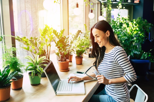 Hermosa joven feliz con laptop en café de la ciudad