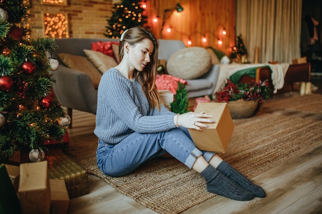 Hermosa joven feliz con regalos de Navidad cerca del árbol de año nuevo