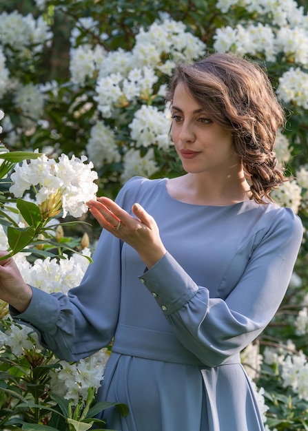 Hermosa joven entre flores blancas de rododendros