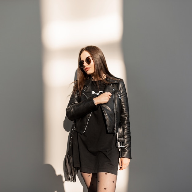 Hermosa joven fresca en ropa de rock estilo negro con gafas de sol de moda