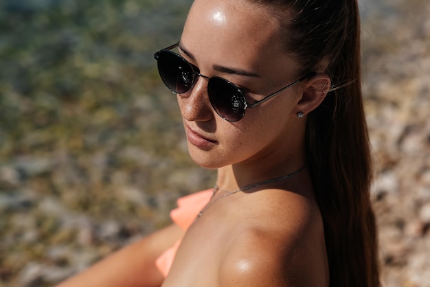 Una hermosa joven con gafas y bikini está sentada en el océano y disfrutando de unas vacaciones en un día soleado Turismo y viajes turísticos Apertura de fronteras y vacaciones