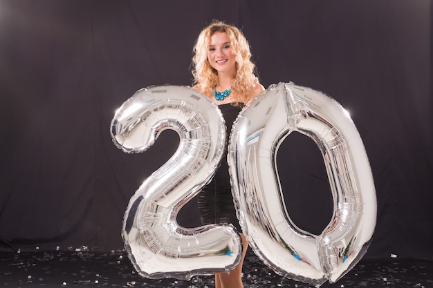 Hermosa joven con globos en forma de número