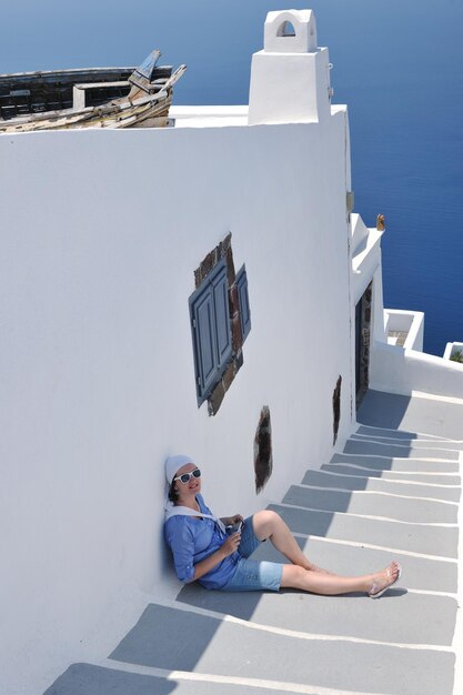 Hermosa joven griega vestida de moda diviértete en las calles de Oia, Santorini, Grecia
