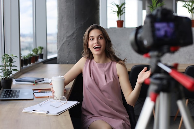 Hermosa joven hablando y sonriendo mientras hace un nuevo video para su blog.