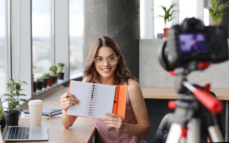 Foto hermosa joven hablando y sonriendo mientras hace un nuevo video para su blog.