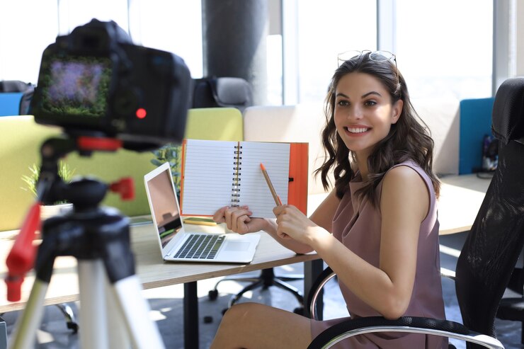 Foto hermosa joven hablando y sonriendo mientras hace un nuevo video para su blog.
