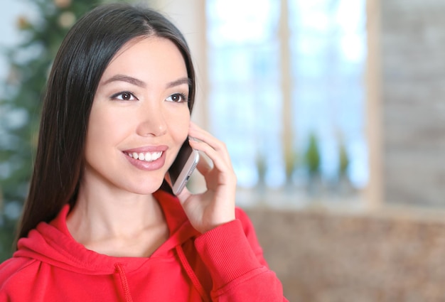 Hermosa joven hablando por teléfono móvil en casa