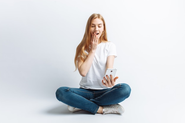 Hermosa joven hablando por teléfono, sorpresa y conmoción a la niña de noticias o descuentos, alegre y positiva