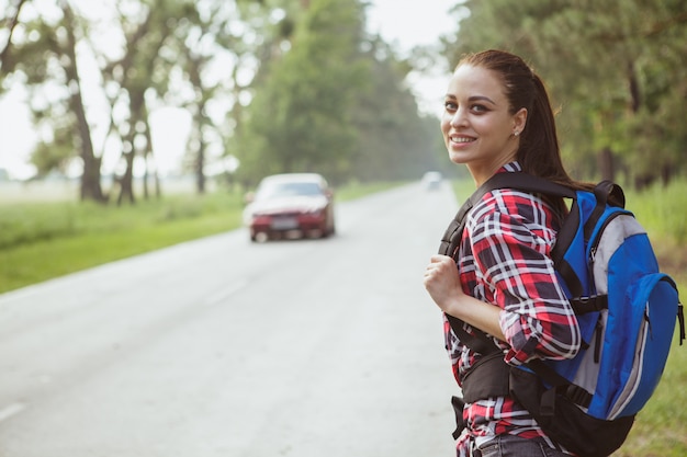 Hermosa joven haciendo autostop en el campo