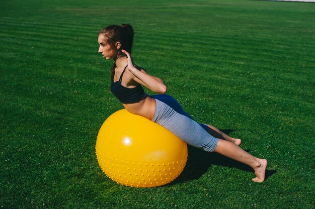 Hermosa joven haciendo ejercicios con fit ball