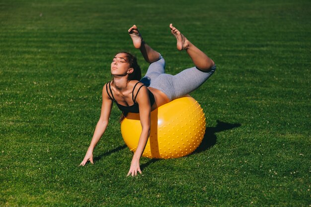 Hermosa joven haciendo ejercicios con fit ball