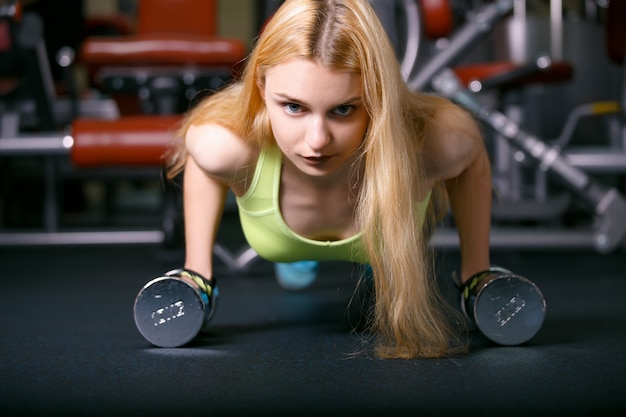 Hermosa joven haciendo ejercicios con pesas en el gimnasio