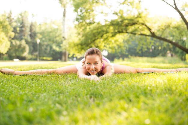 Hermosa joven haciendo ejercicios de relajación y estiramiento en el parque.