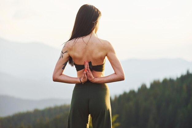 Hermosa joven haciendo ejercicios de yoga Majestuosas montañas de los Cárpatos Hermoso paisaje de naturaleza virgen