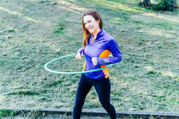 Hermosa joven haciendo hula hoop al atardecer en un concepto de park point deporte gimnasia rítmica cuidado personal