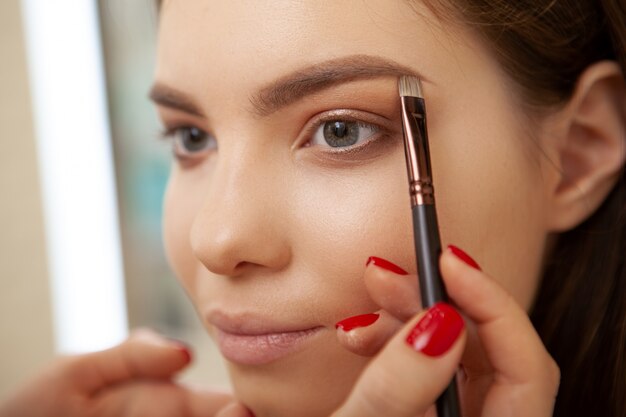 Hermosa joven haciendo maquillaje profesional hecho