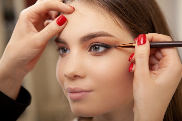 Hermosa joven haciendo maquillaje profesional hecho