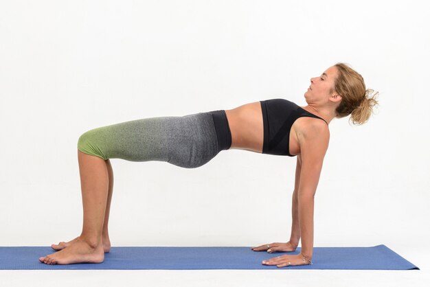 Hermosa joven haciendo yoga en blanco