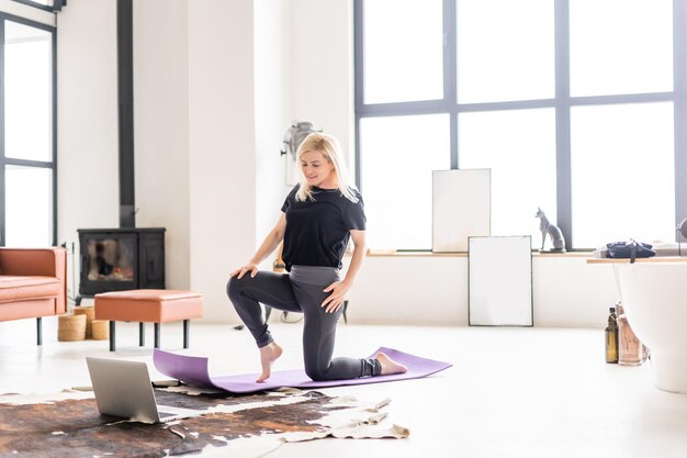 Hermosa joven haciendo yoga en casa.