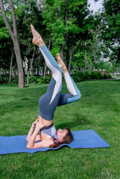 Hermosa joven haciendo yoga en un césped verde