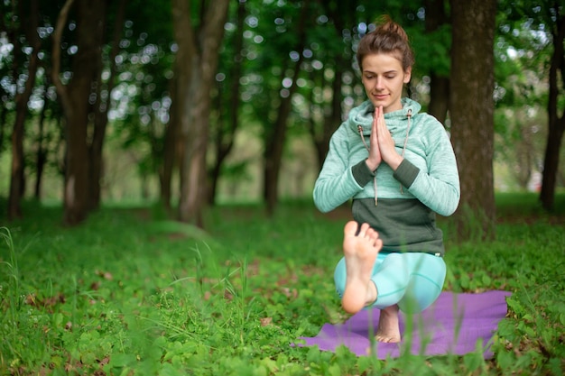 Hermosa joven haciendo yoga en la naturaleza