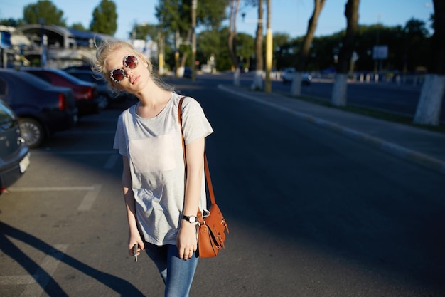 La hermosa joven hipster con gafas de sol posa en la calle durante el verano