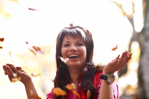 Foto hermosa joven con hojas caídas en el bosque de otoño