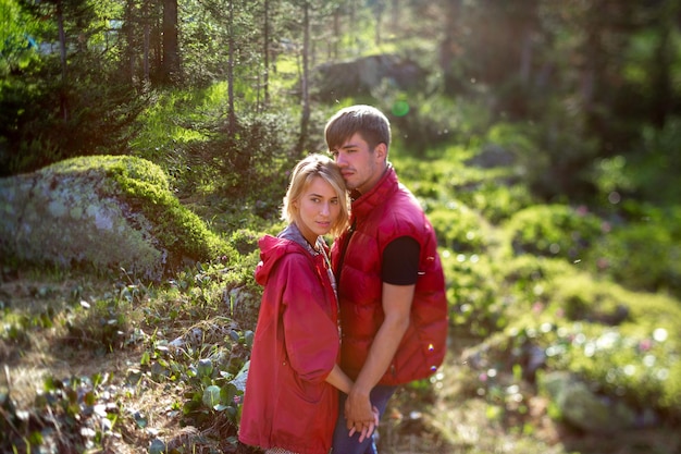 Hermosa joven y hombre caminan abrazos y besos en la naturaleza montañosa con efecto de cambio de inclinación