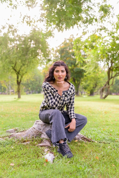 Hermosa joven inconformista indio sentado en el parque al aire libre