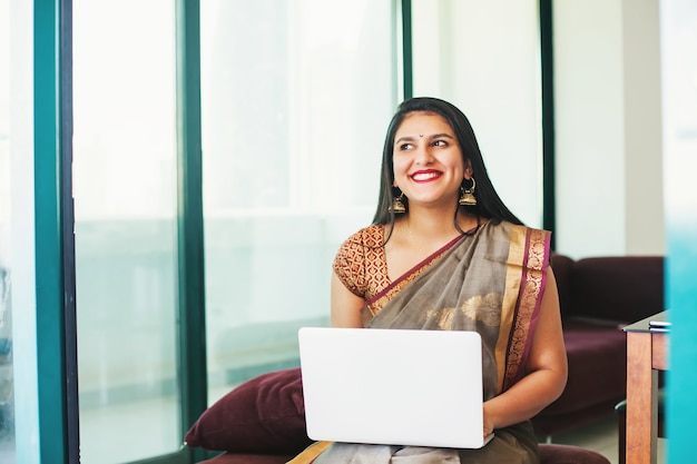 Hermosa joven india inspirada en un sari usando su computadora portátil